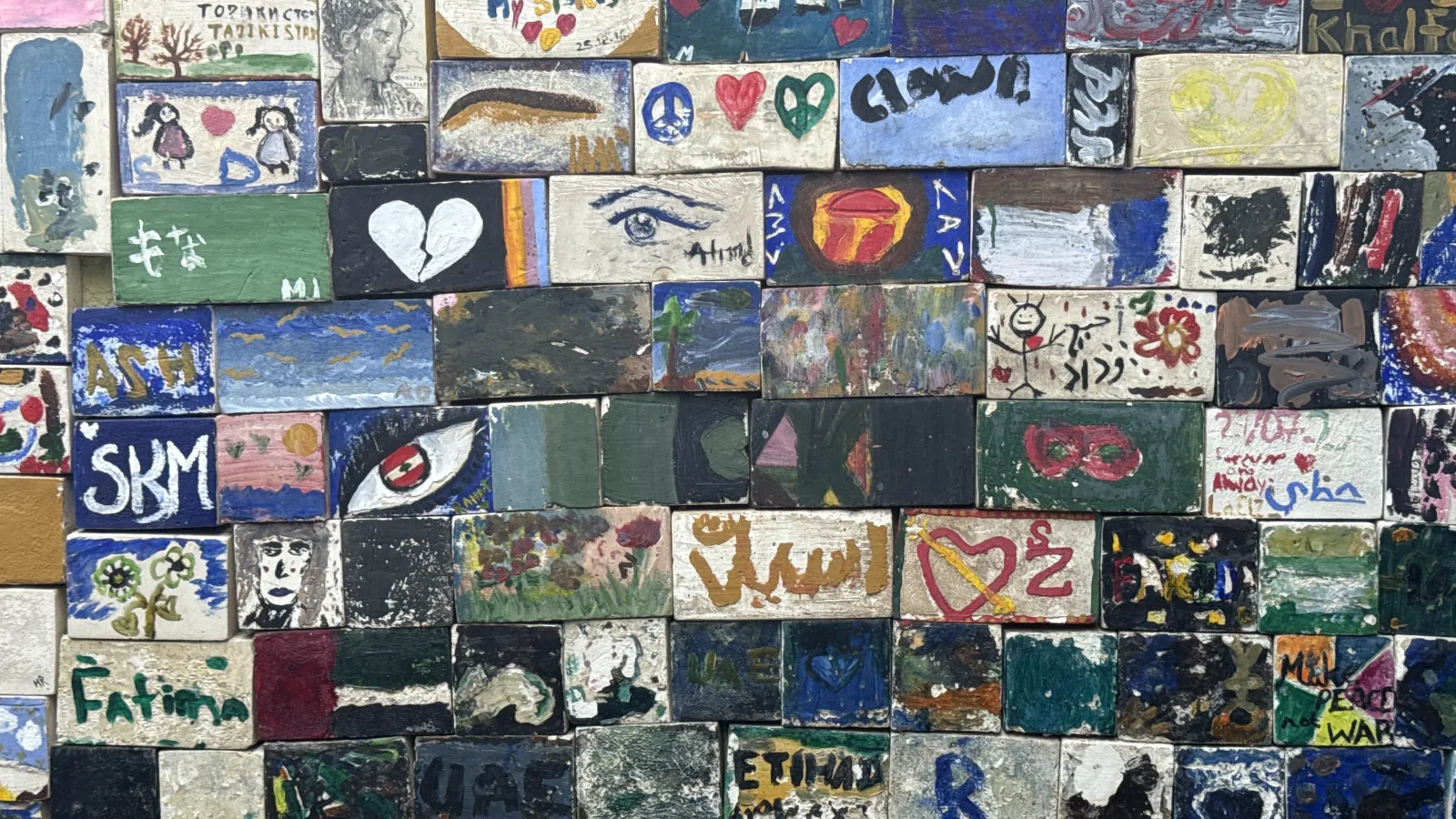 A wall of small tiles, each one painted by a different person